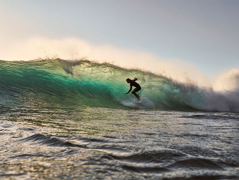 Experienced surfer riding a powerful wave in Cape Town, South Africa.